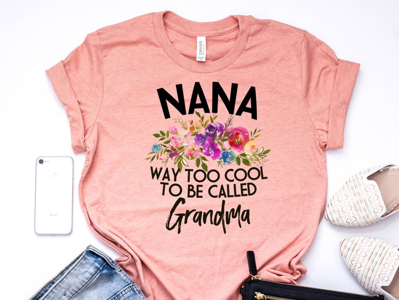 Puede incluir: Una camiseta rosa con un dise&ntilde;o floral y el texto "NANA WAY TOO COOL TO BE CALLED GRANDMA".