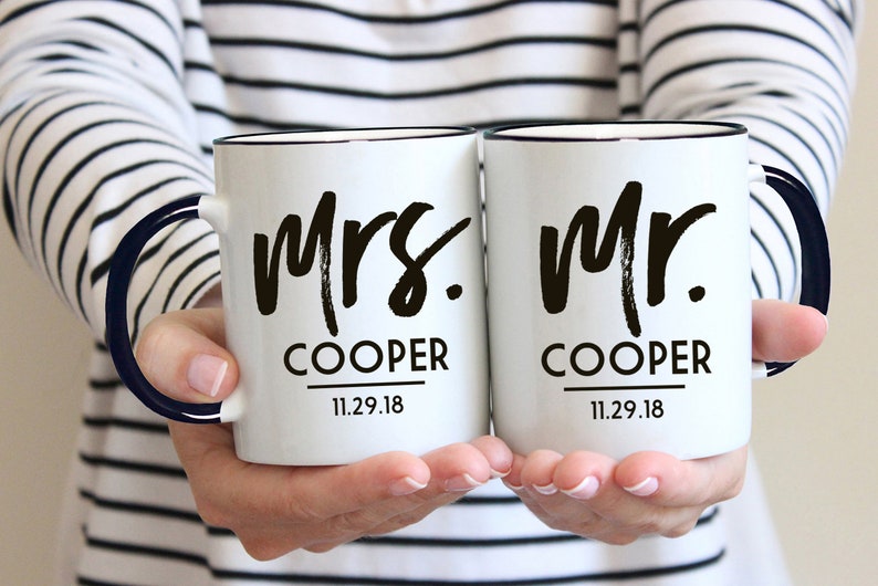 May include: Two white ceramic mugs with black handles and black lettering. The mugs say "Mrs. Cooper 11.29.18" and "Mr. Cooper 11.29.18".
