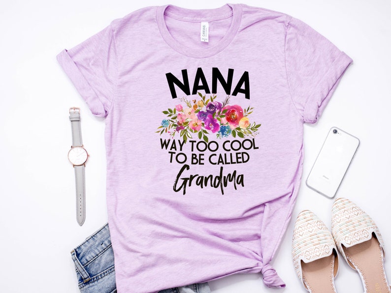 Puede incluir: Una camiseta lavanda con un dise&ntilde;o floral y el texto "NANA WAY TOO COOL TO BE CALLED GRANDMA".