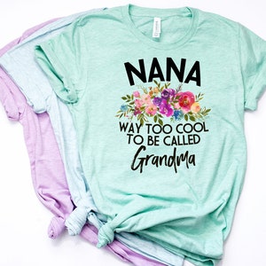 Puede incluir: Una camiseta verde claro con un dise&ntilde;o floral y el texto "NANA WAY TOO COOL TO BE CALLED GRANDMA".