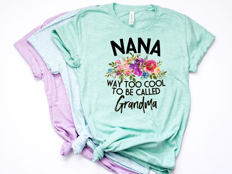 Puede incluir: Una camiseta verde claro con un dise&ntilde;o floral y el texto "NANA WAY TOO COOL TO BE CALLED GRANDMA".