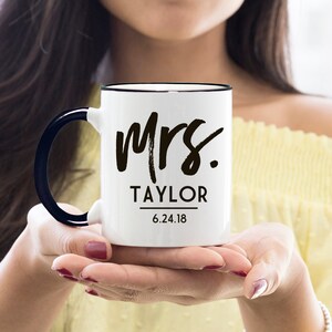 May include: White ceramic mug with a black rim and handle. The mug has black text that reads "Mrs. Taylor 6.24.18".