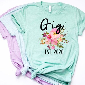 May include: A light green t-shirt with a floral design and the text "Gigi Est. 2020".