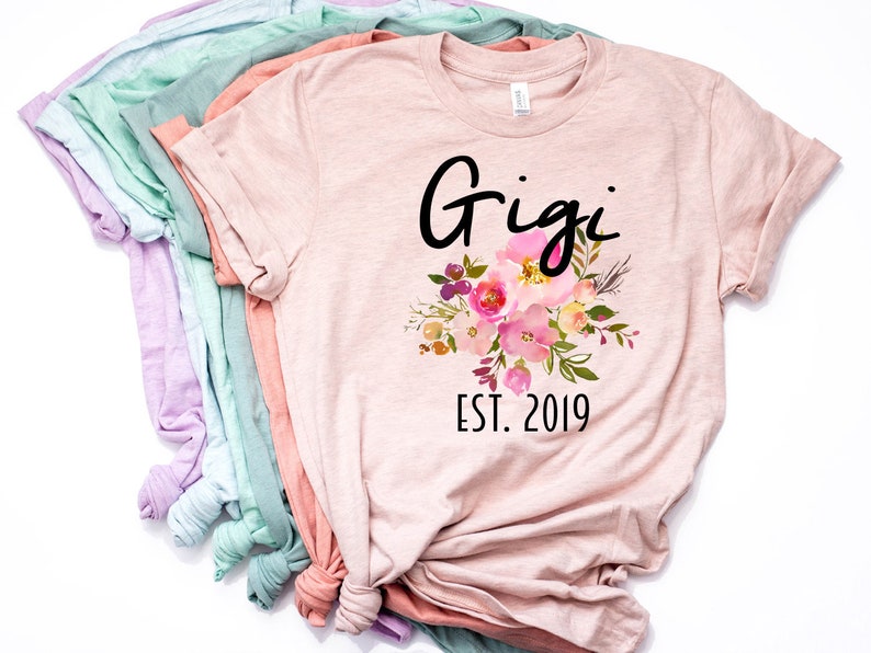 May include: A pink t-shirt with the text "Gigi Est. 2019" and a floral design.