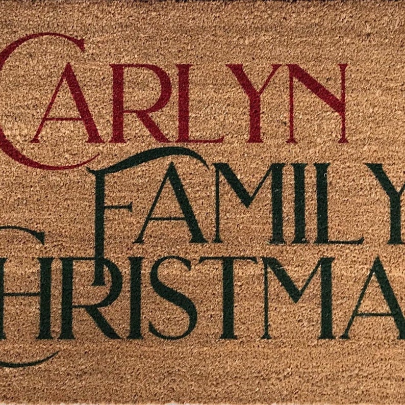 Puede incluir: Una alfombra de coco marr&oacute;n con el texto "Carly Family Christmas" en letras rojas y verdes.