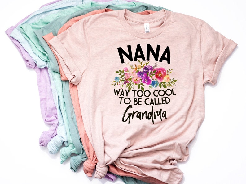 Puede incluir: Camiseta rosa con un dise&ntilde;o floral y el texto "NANA WAY TOO COOL TO BE CALLED GRANDMA".