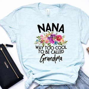 Puede incluir: Camiseta azul claro con un dise&ntilde;o floral y el texto "NANA WAY TOO COOL TO BE CALLED GRANDMA".