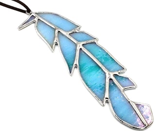 May include: A stained glass feather ornament with a blue and purple iridescent finish. The feather is suspended from a brown leather cord.