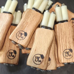 May include: A collection of wooden tools with light-colored grain, each featuring a branded logo with the text 19C and a small leaf icon. Each tool has two white cylindrical rollers attached to the top with metal hardware and black springs.