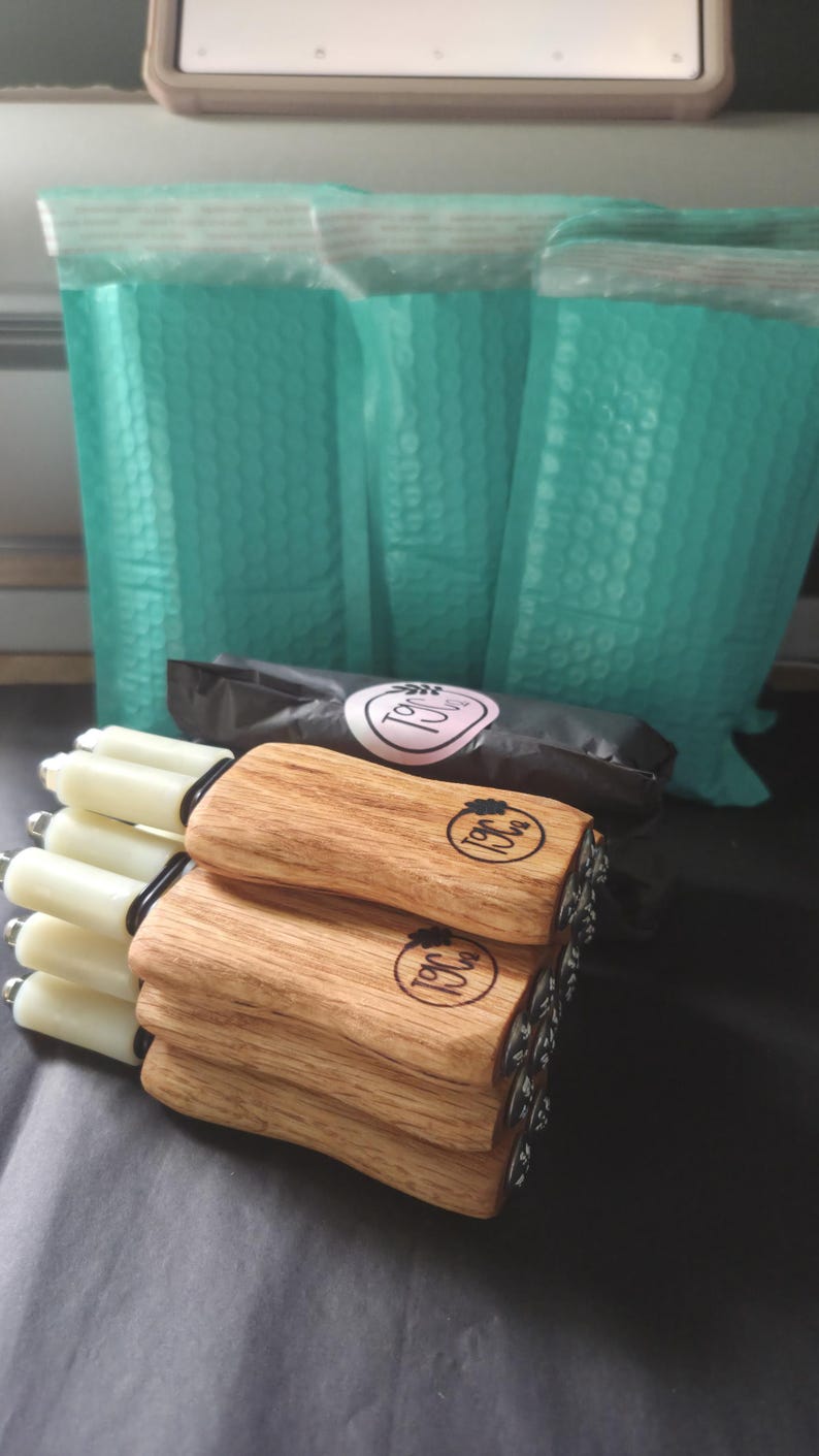 May include: A stack of four handheld tools with light-colored wooden handles and white cylindrical tips. Each handle features a circular brand logo with the text T9C. The tools are arranged horizontally, with the wooden handles facing forward.