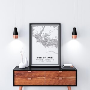 Puede incluir: Impresi&oacute;n de mapa en blanco y negro de Puerto Espa&ntilde;a, Trinidad y Tobago, con las coordenadas 10.6463&deg;N 61.5088&deg;W, enmarcada en un marco negro y colgada en una pared blanca sobre una c&oacute;moda de madera con frentes de cajones negros.