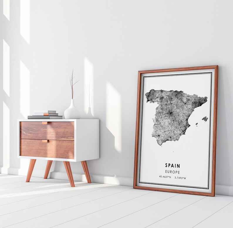May include: A black and white print of a map of Spain with the text "SPAIN EUROPE 40.4637&deg;N 3.7492&deg;W" in a brown frame.