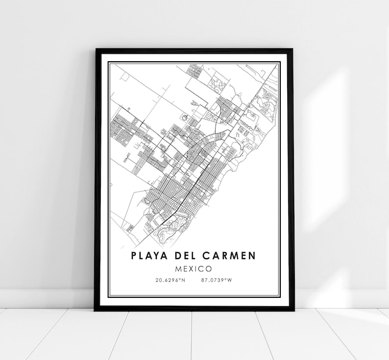 May include: Black and white framed map print of Playa del Carmen, Mexico. The map details the city's streets and layout, with the city name and coordinates displayed below. The print is encased in a black frame.