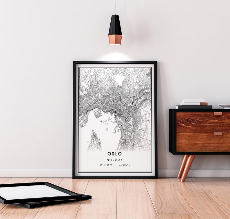 May include: Black and white map print of Oslo, Norway with the city name and coordinates in the bottom right corner. The print is framed in a black frame and hanging on a white wall.