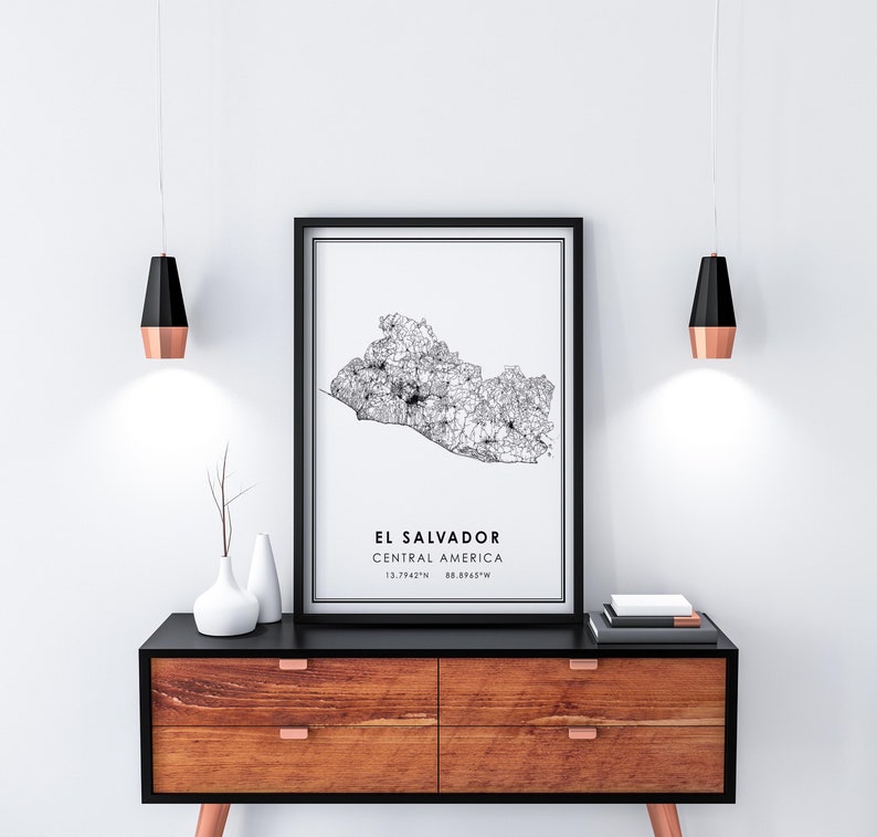 May include: Black and white line art map print of El Salvador, Central America. The print is framed in a black frame and hanging on a white wall above a wooden dresser.