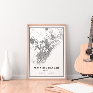 May include: A framed map print of Playa del Carmen, Mexico, in black and white, with coordinates. A wooden acoustic guitar stands on a black stand to the right. A white vase and a small gold vase are on the left.