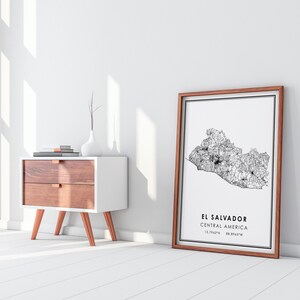 May include: A framed black and white map of El Salvador, Central America. The map shows the country's roads and cities. The frame is brown wood.
