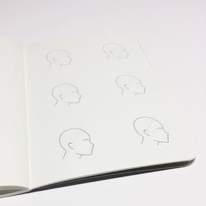 May include: A notebook page with six simple line drawings of a person's head in profile. The drawings are all the same size and are arranged in two rows of three.