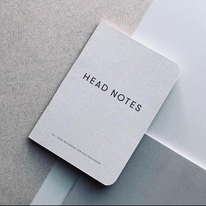 May include: A white notebook with the text "HEAD NOTES 84-PAGE NOTEBOOK FOR HAIR DESIGNERS" printed on the cover.