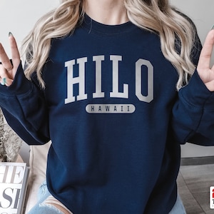 May include: A navy blue sweatshirt with the text "HILO HAWAII" printed in white.