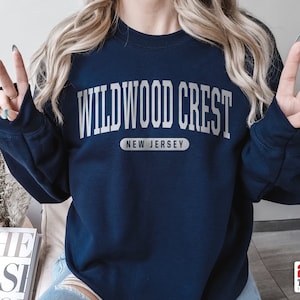 May include: A navy blue sweatshirt with the text "WILDWOOD CREST NEW JERSEY" in white lettering.