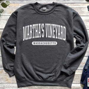 以下が含まれることがあります： 「Martha's Vineyard Massachusetts」と白文字で書かれた濃いグレーのスウェットシャツです。