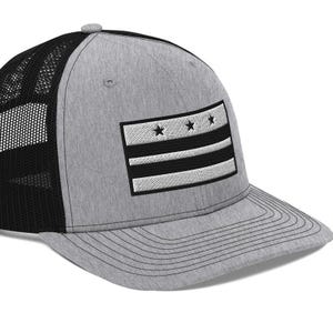 May include: A gray and black trucker hat with a white and black embroidered flag of Washington, D.C. on the front.