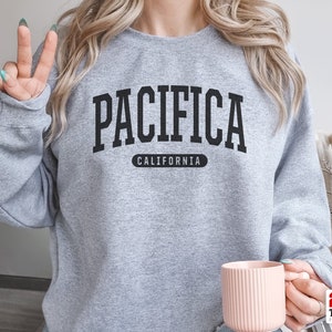 May include: Gray sweatshirt with black text that reads "Pacifica California".