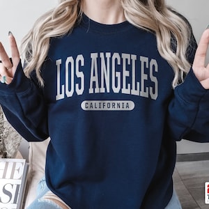 May include: A navy blue sweatshirt with the text "LOS ANGELES CALIFORNIA" in white lettering.