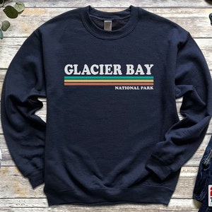 May include: A navy blue sweatshirt with a white graphic that says "Glacier Bay National Park" in a retro style with colorful stripes.