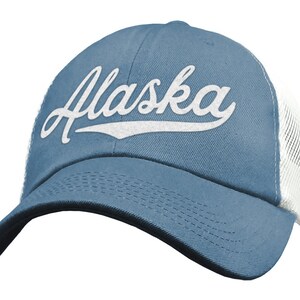 May include: A blue and white trucker hat with the word "Alaska" in white cursive lettering on the front.
