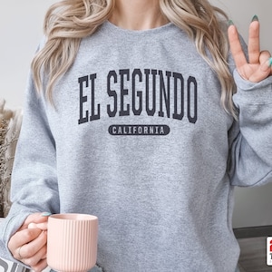 May include: Gray sweatshirt with the text "EL SEGUNDO CALIFORNIA" in black lettering.