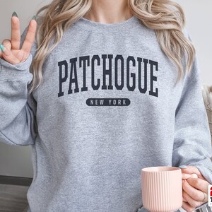 May include: A gray sweatshirt with the text "Patchogue New York" in black lettering.
