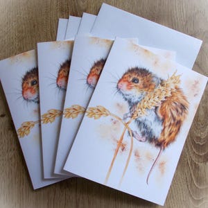 May include: Set of five blank greeting cards featuring a watercolor illustration of a brown and white mouse sitting on a stalk of wheat. The mouse has a long tail and is looking to the right. The background is a light brown color.