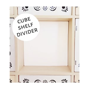 May include: A white wooden cube shelf divider with the text "CUBE SHELF DIVIDER" in a black circle.