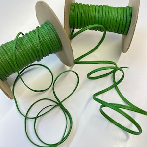 May include: Two spools of green cord wrapped around cardboard spools. The cord is a textured, woven material.