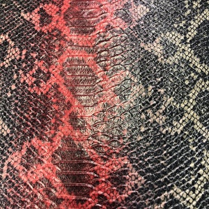 K&ouml;nnte beinhalten: Nahaufnahme eines Schlangenlederstoffs mit einem roten und schwarzen Muster. Der Stoff hat eine strukturierte Oberfl&auml;che und eine gl&auml;nzende Oberfl&auml;che.