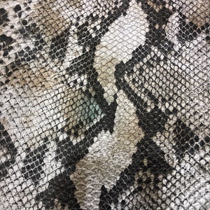 K&ouml;nnte beinhalten: Nahaufnahme eines schwarz-wei&szlig;en Schlangenhautmusters. Das Muster besteht aus kleinen, &uuml;berlappenden Schuppen.