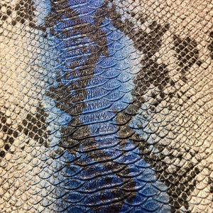 K&ouml;nnte beinhalten: Nahaufnahme eines blauen und silbernen Schlangenhautmusters. Das Muster besteht aus kleinen, &uuml;berlappenden Schuppen.