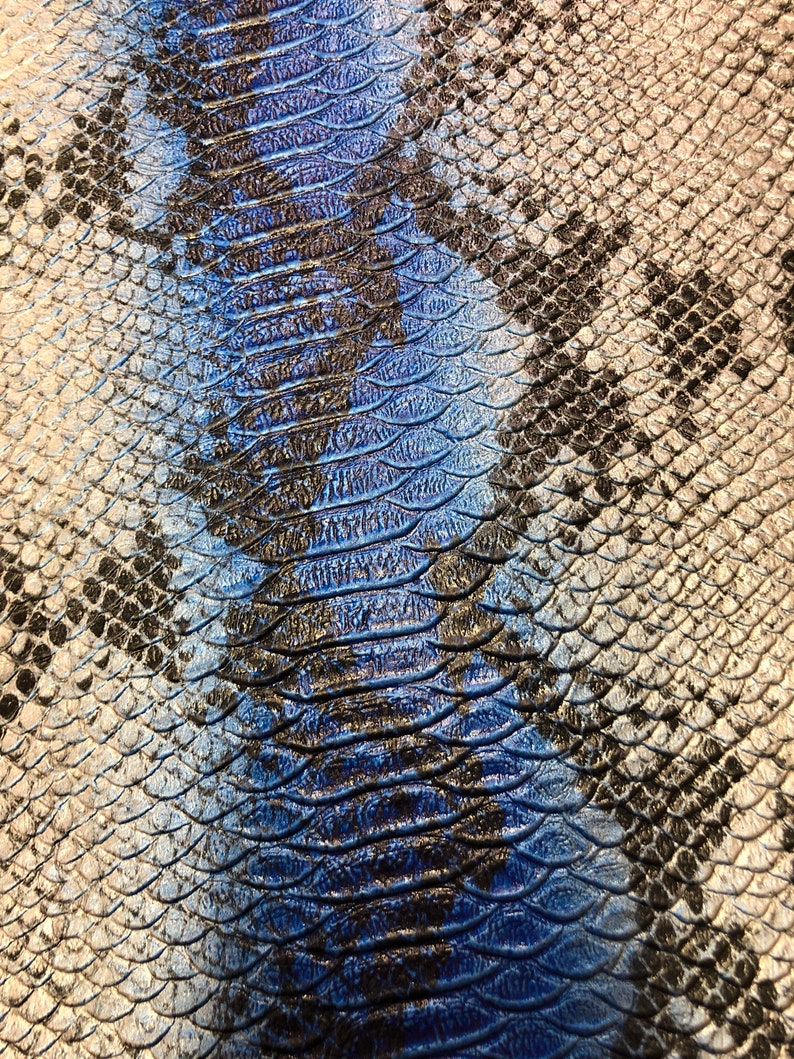 K&ouml;nnte beinhalten: Nahaufnahme eines blauen und silbernen Schlangenhautmusters. Das Muster besteht aus kleinen, &uuml;berlappenden Schuppen.