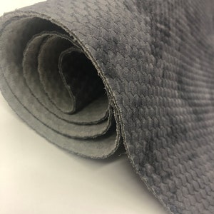 May include: A roll of dark gray textured fabric with a subtle pattern. The fabric is soft and has a slightly rough texture.