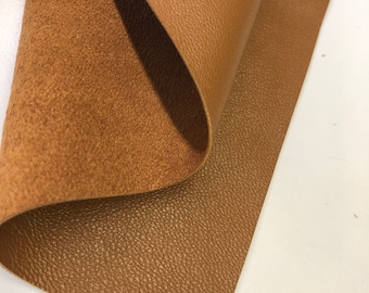 May include: A close-up of a piece of brown leather with a textured surface. The leather is folded in half, showing the smooth side and the textured side.