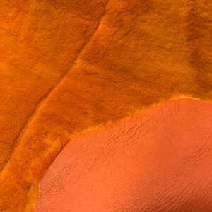 May include: A piece of orange faux fur fabric with a smooth orange leather backing.