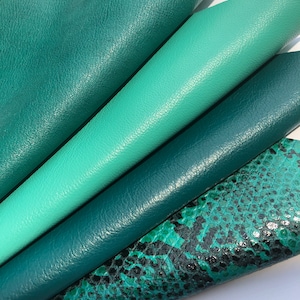 May include: Four different shades of green leather fabric swatches. The swatches are arranged in a stack, with the darkest green on the bottom and the lightest green on top. The top swatch has a subtle snakeskin pattern.