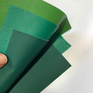 May include: Three pieces of green fabric with a textured surface. The fabric is folded in a triangular shape.