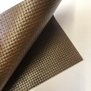 May include: A close-up of a brown woven leather fabric. The fabric has a textured surface and a subtle sheen.