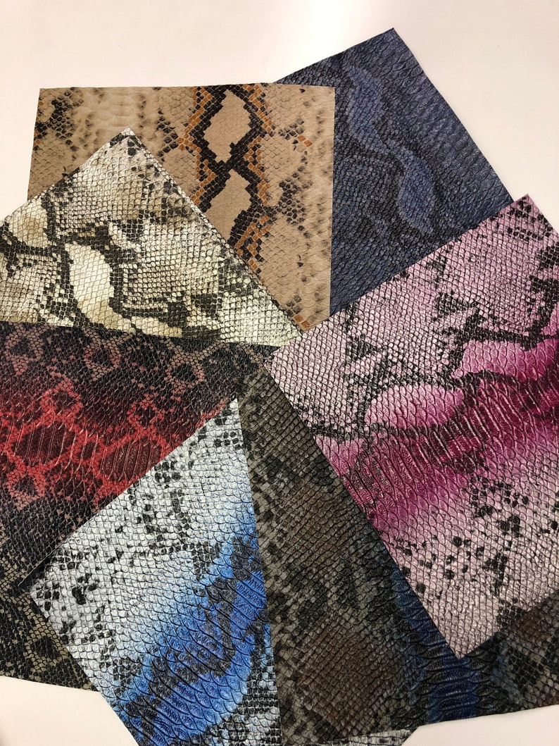 K&ouml;nnte beinhalten: Sortiment von Stoffproben in Schlangenlederoptik in verschiedenen Farben und Mustern, darunter Braun, Schwarz, Wei&szlig;, Blau, Rosa und Rot.