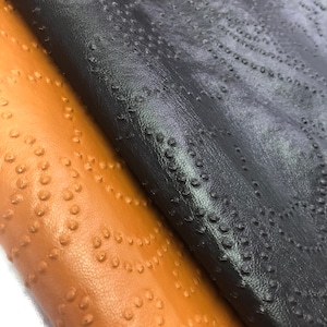 May include: Two pieces of embossed leather fabric. One piece is brown and the other is black.