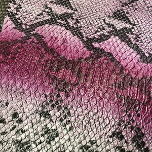 K&ouml;nnte beinhalten: Nahaufnahme eines Stoffes mit Schlangenhautmuster in einem Farbverlauf von Pink und Schwarz.