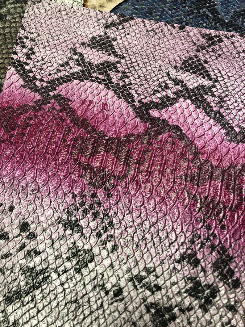 K&ouml;nnte beinhalten: Nahaufnahme eines Stoffes mit Schlangenhautmuster in einem Farbverlauf von Pink und Schwarz.